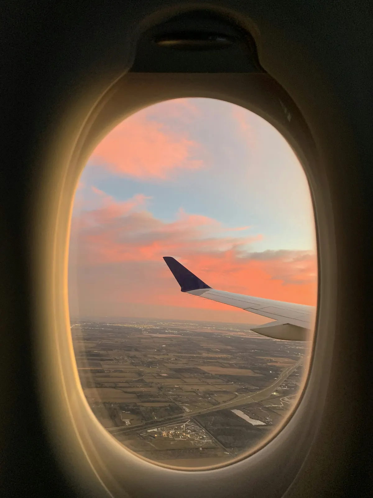 Pink evening sky and a wingtip through a cabin window